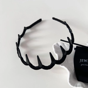 Close-up of black spiked headband with fabric wrap and gothic punk style on a tray