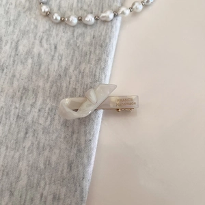 Detail of white pearlescent bow hair clip with gold France Handmade engraving