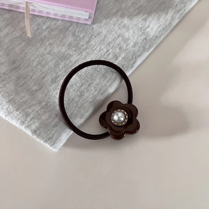 Detailansicht eines eleganten Haargummis mit Perle und goldenem Strukturrahmen