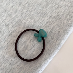 Detail of high-elastic purple hair tie with green resin charm and handmade engraving