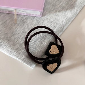 Detail of elastic hair tie with black geometric and heart charms featuring L·T engraving