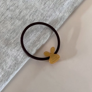 Detail of yellow rabbit charm with France Handmade engraving on brown elastic hair tie