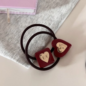 Detail view of red resin hair ties with gold metal heart charms featuring L.T engraving