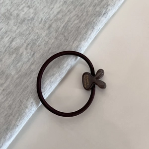Macro detail of brown high-elastic hair tie with a resin rabbit charm and gold lettering