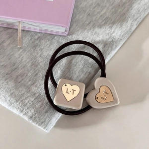 Detailed macro view of heart and square acrylic charms on a high-elastic hair tie