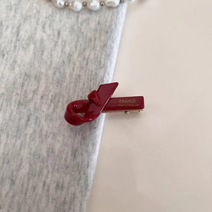 Close-up of deep red bow hair clip with gold France Handmade lettering and metal spring