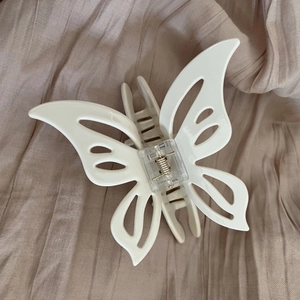 Close-up of cream beige acetate butterfly hair claw with hollow wings and metal spring