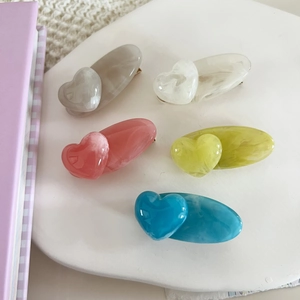Detailed macro view of heart-shaped acrylic hair clips with colorful marble texture finish