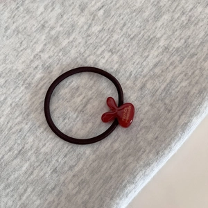 Close-up of elastic hair tie with red resin charm featuring gold France Handmade text
