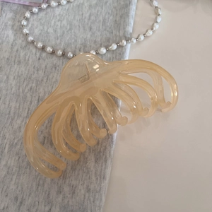 Détail d'une grande pince à cheveux ambre champagne avec une texture de glace lisse