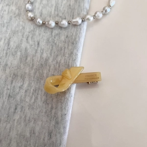 Detail of ginger acetate knot bow hair clip with gold France Handmade engraved text