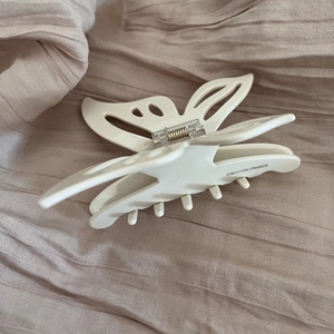 Elegant beige butterfly acetate hair claw clip with cutout details on satin fabric