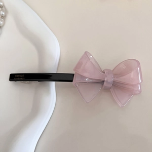 Dettaglio del fermaglio per capelli a fiocco in acrilico rosa fatto a mano su un piatto di porcellana