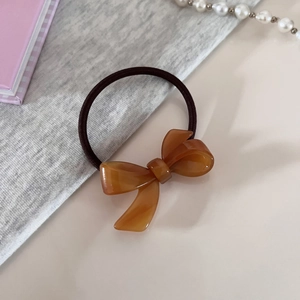 Elegant amber acetate bow hair tie with high elastic band on cozy desktop setting