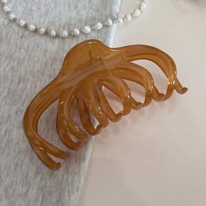 Gros plan d'une grande pince à cheveux ambre translucide montrant sa structure robuste