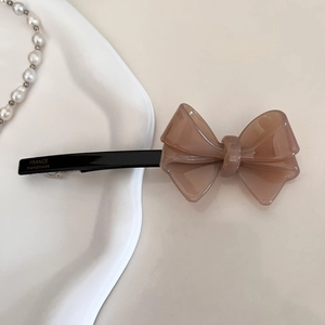 Dettaglio di un fermaglio per capelli a fiocco in acetato marrone con scritta dorata