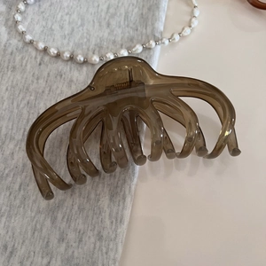 Détail d'une grande pince à cheveux marron translucide sur un fond minimaliste élégant