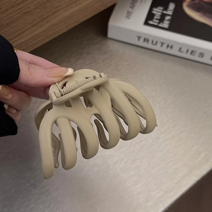 Close-up of matte beige large hair claw clip showing smooth curved design and metal spring