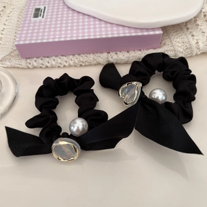 Gros plan de chouchous en satin noir avec rubans et pendentifs élégants en perles