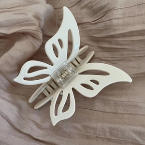 Detailed close-up of a cream butterfly-shaped hair claw clip with a hollow design