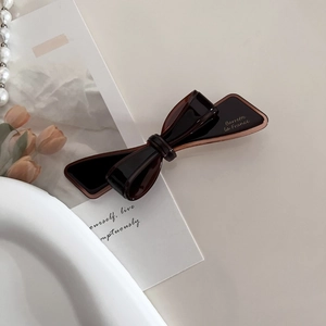 Detail of elegant dark brown bow hair clip with Barrette La France gold lettering