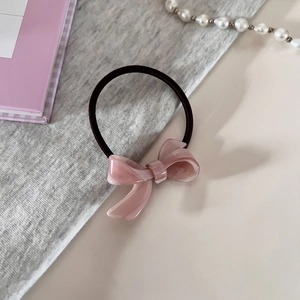 Detail of pink acetate bow hair tie with marble texture and black elastic band