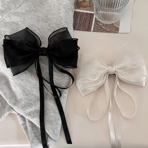 Detail of elegant black and beige double-layered organza bow clips with long ribbons
