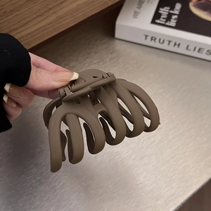 Macro detail of large matte brown hair claw clip with cross-teeth design and metal spring