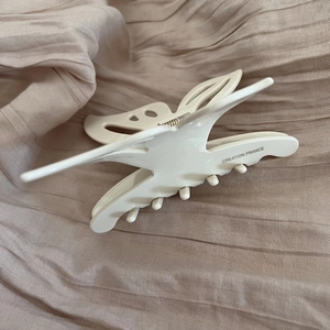 Close-up of beige acetate butterfly hair claw clip with Creation France engraving