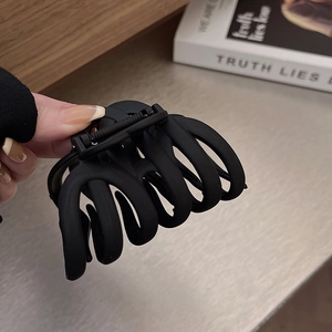 Detail of a large matte black hair claw clip showing textured grip and wide design