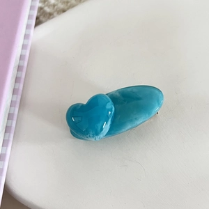 Close-up of heart-shaped acrylic hair clip with blue marble texture and glossy finish