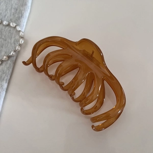 Détail d'une grande pince à cheveux ambrée avec finition transparente et dents solides