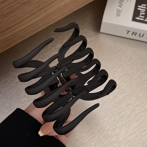 Large matte black shark hair claw clip for thick hair shown in a lifestyle setting