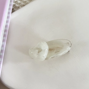 Detailed close-up of cream marble patterned heart hair clip on a minimalist background