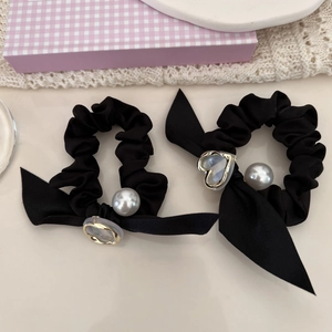 Détail de chouchous en satin noir avec perles blanches et breloques coeur doré