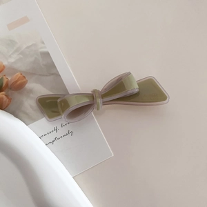 Detail of a French-style acetate bow hair clip in olive green and purple finish