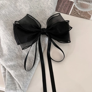 Elegant black mesh bow hair clip with long ribbons on soft gray knit fabric