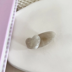 Macro view of marbled gray acetate hair clip with 3D heart on white decorative tray