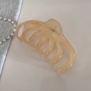 Détail macro d'une pince à cheveux en résine ambre avec dents pieuvre sur fond blanc