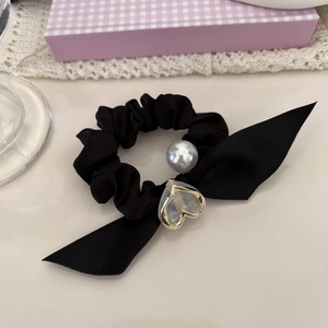 Détail d'un chouchou en satin noir avec perle grise, cœur doré et nœud élégant