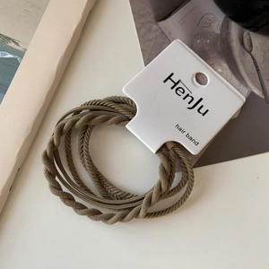 Detailed view of three brown spiral hair ties with durable braided texture on white card