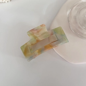 Close-up of a large square marble acetate hair claw clip with colorful pastel swirls