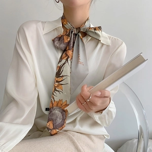 Détail d'un foulard étroit à motif tournesol noué en ruban sur une chemise blanche