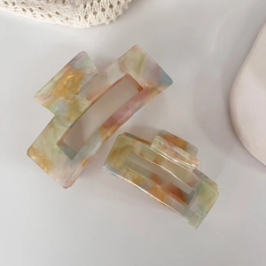 Detailed view of iridescent acetate hair claws in two sizes with colorful marble patterns