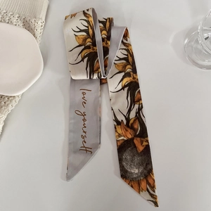 Détail d'un twilly en soie avec motif de tournesol et texte Love Yourself sur tissu doux
