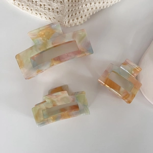 Detailed macro view of three acetate marble pattern claw clips on white surface