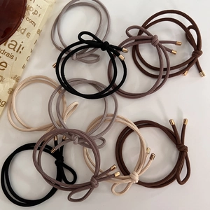 Detail of high-elastic bow hair ties in coffee tones with gold metal accents and textures