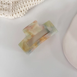 Detailed view of square acetate hair claw with pastel marble texture and glossy finish