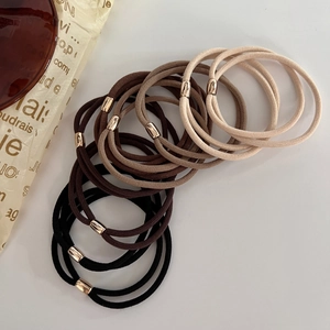 Dettaglio degli elastici per capelli in toni terra con perline metalliche dorate