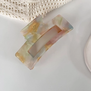 Detail of artistic iridescent acetate hair claw clip with colorful marble pattern